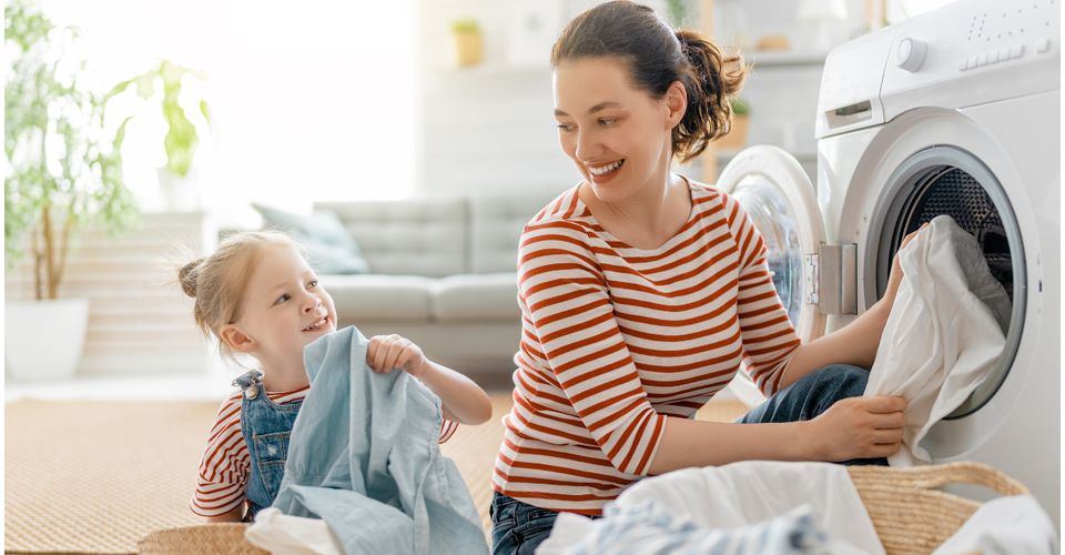 mum and child putting laundry in a washing machine