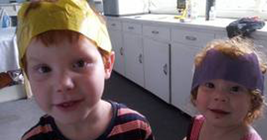 two cute children wearing paper hats