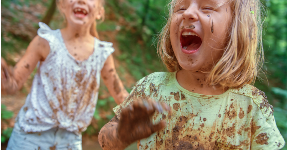 Kids splashing at in mud during outdoor messy play.