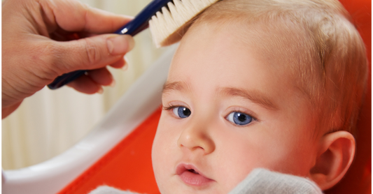 Parent gently brushing baby’s hair with a soft baby brush.