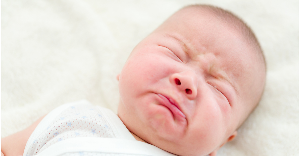 Newborn baby crying while lying down, showing typical infant communication behaviour
