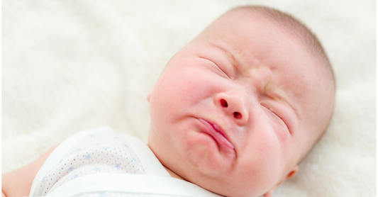 Newborn baby crying while lying down, showing typical infant communication behaviour
