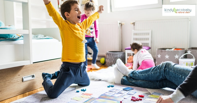 boy in yellow shirt with siblings around him cheering while playing a board game with them