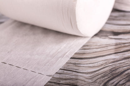 Roll of bamboo nappy liners with a textured surface on a wooden floor