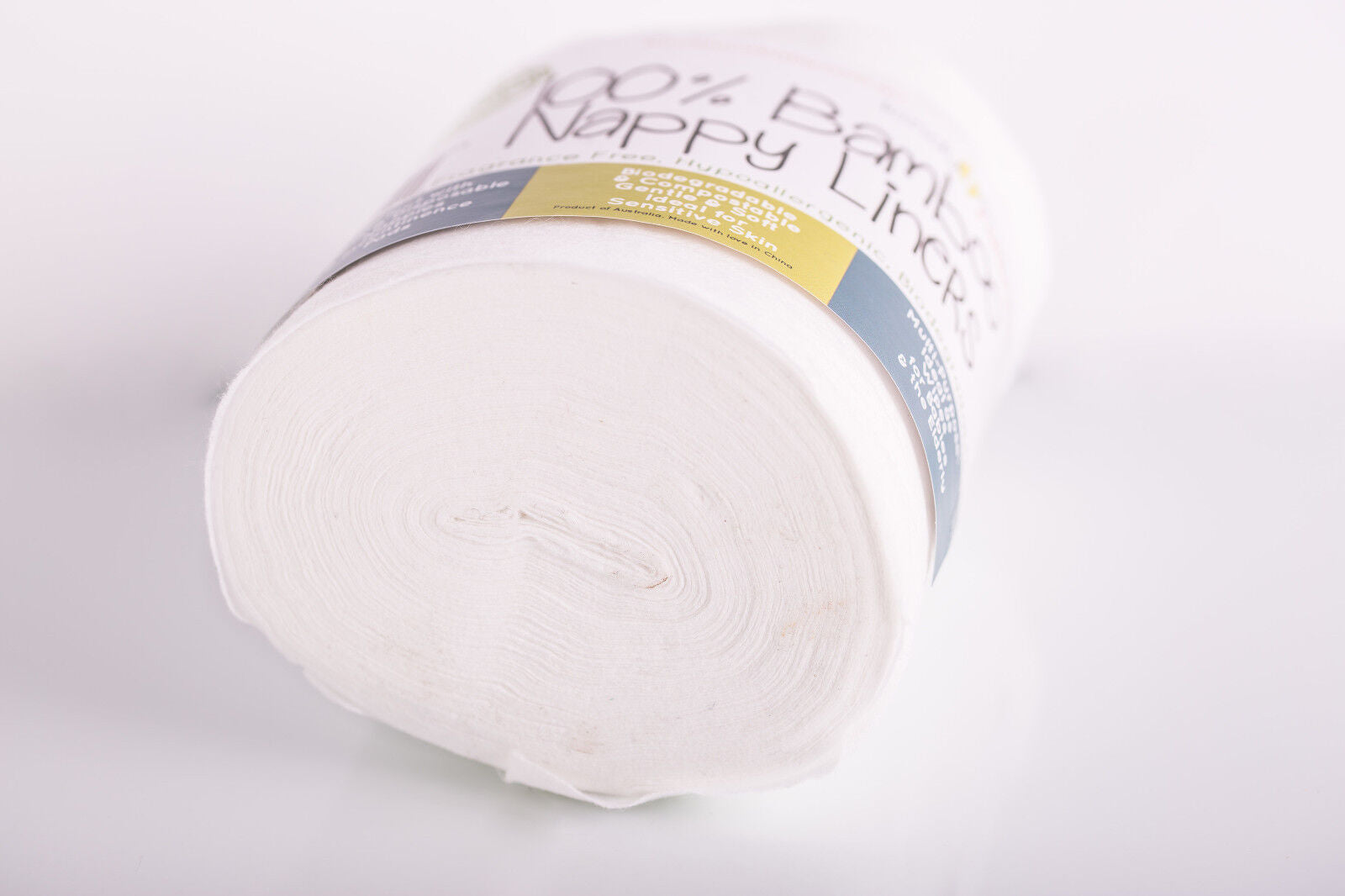 Roll of white bamboo nappy liners with a label on a light gray background